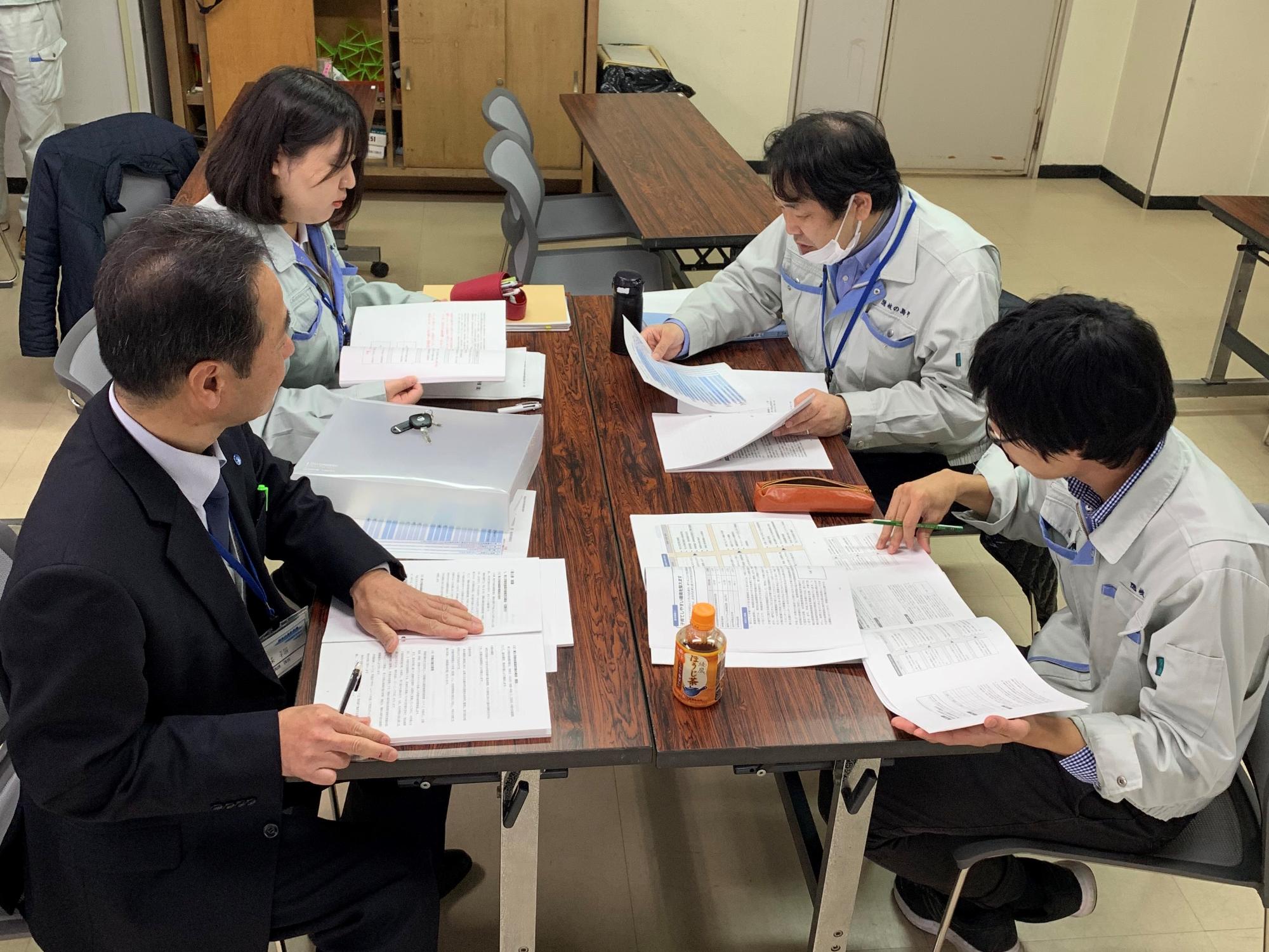 男性3人と女性1人のグループで話し合いをしている職員たちの写真