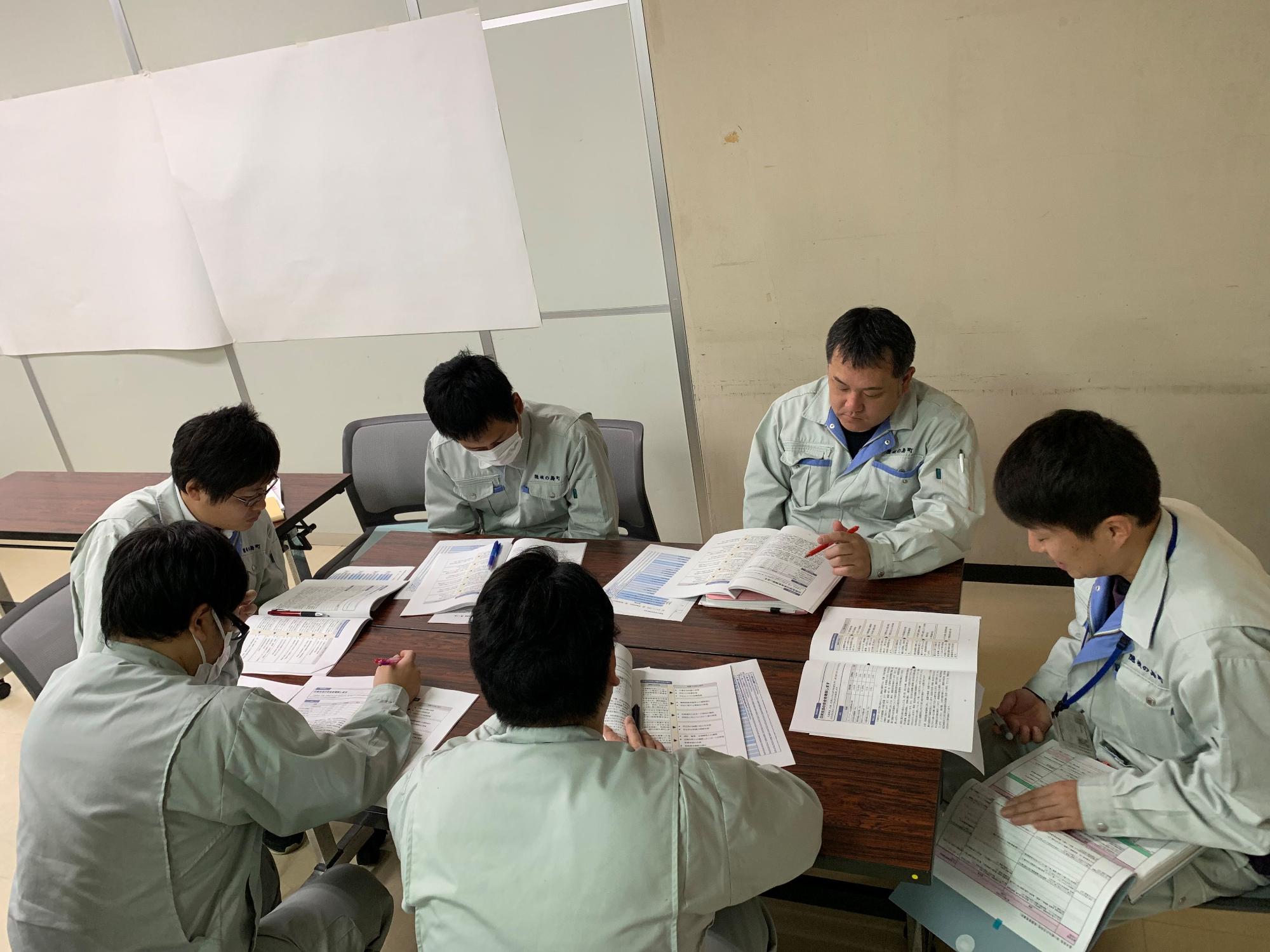 資料を見ながら話し合いをしている6人グループの職員たちの写真