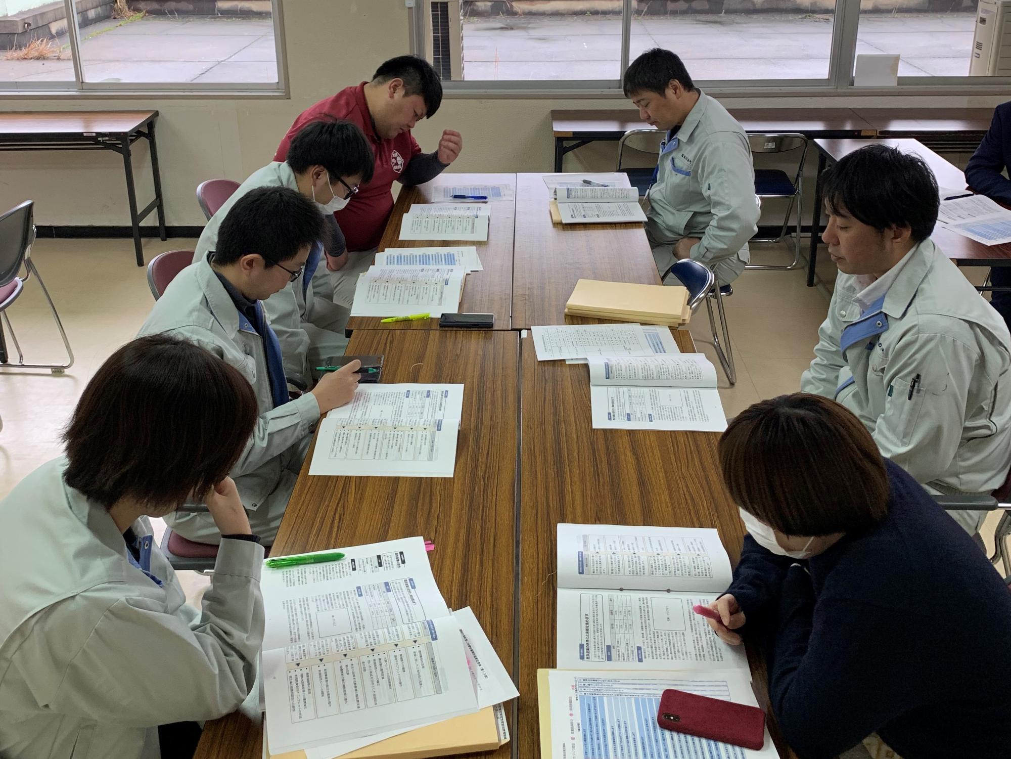7人のグループで資料を見ながら話し合いをしている職員たちの写真