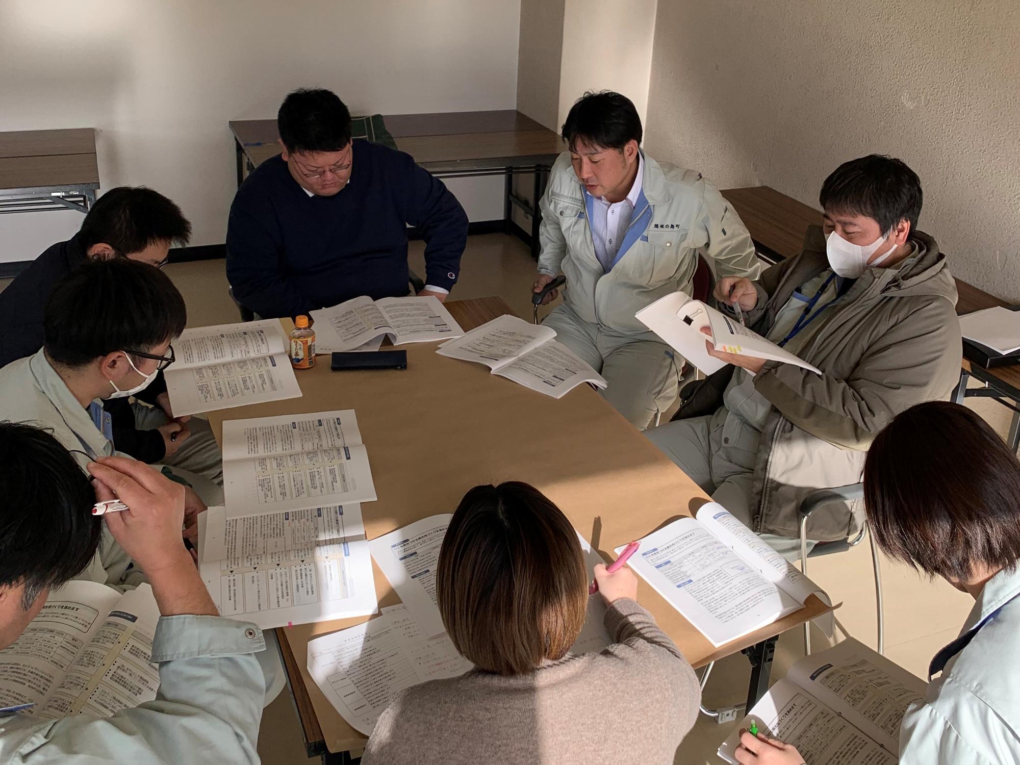 資料を見ながら話し合いをしている8人グループの職員たちの写真