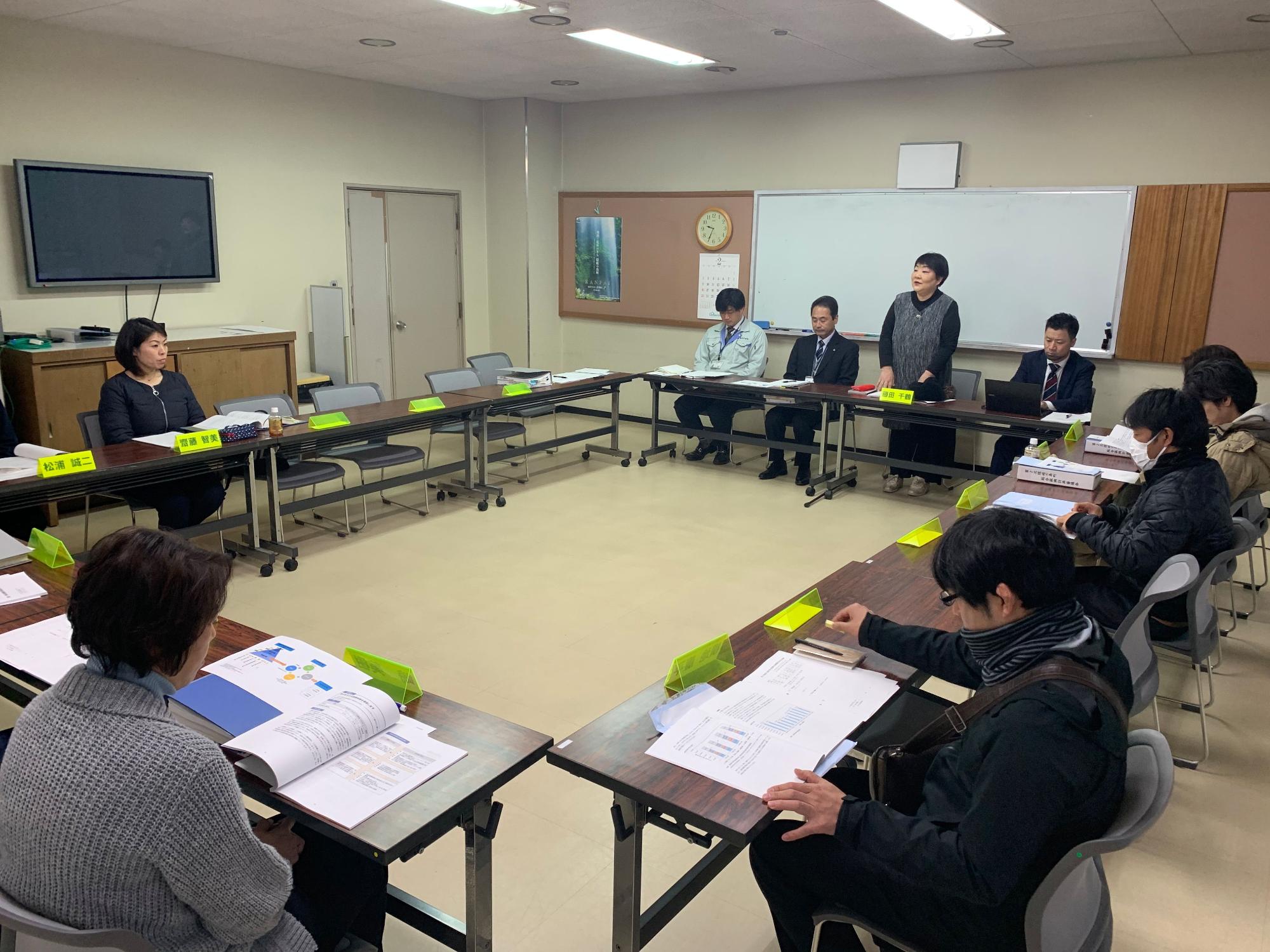 審議会で発言している女性とそれを聞いている参加者たちの写真