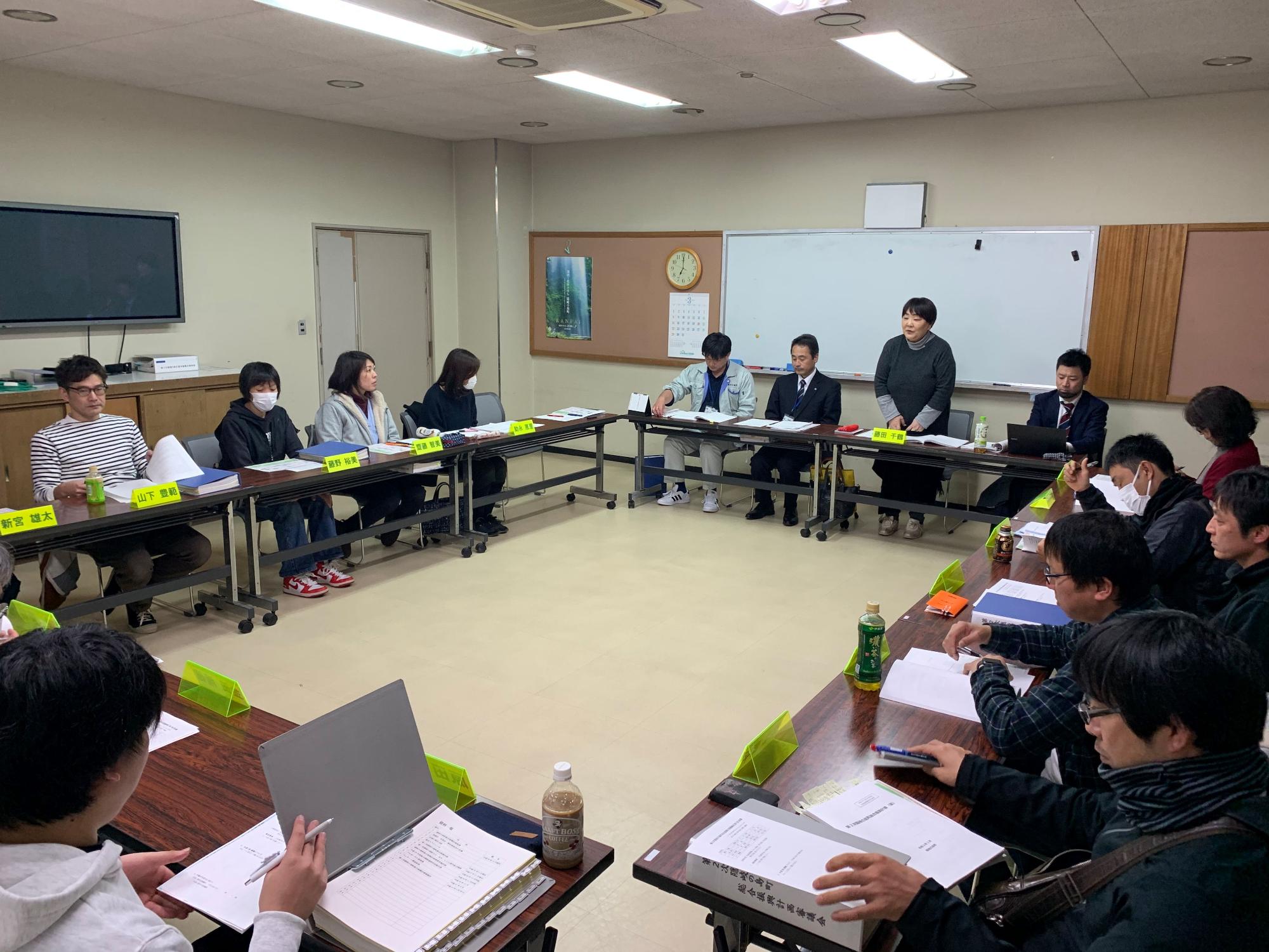 立ち上がって発言している藤田会長とそれを聞いている参加者たちの写真