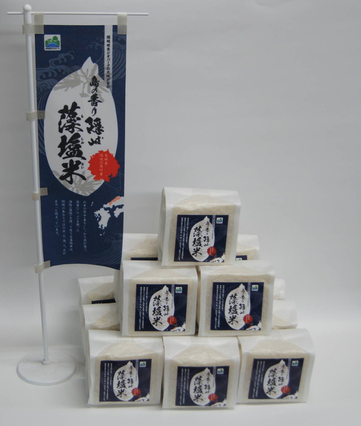 包装され積み上げられた「島の香り隠岐藻塩米」とその旗の写真