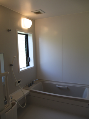 浴槽とシャワー、鏡が備え付けられた浴室の写真