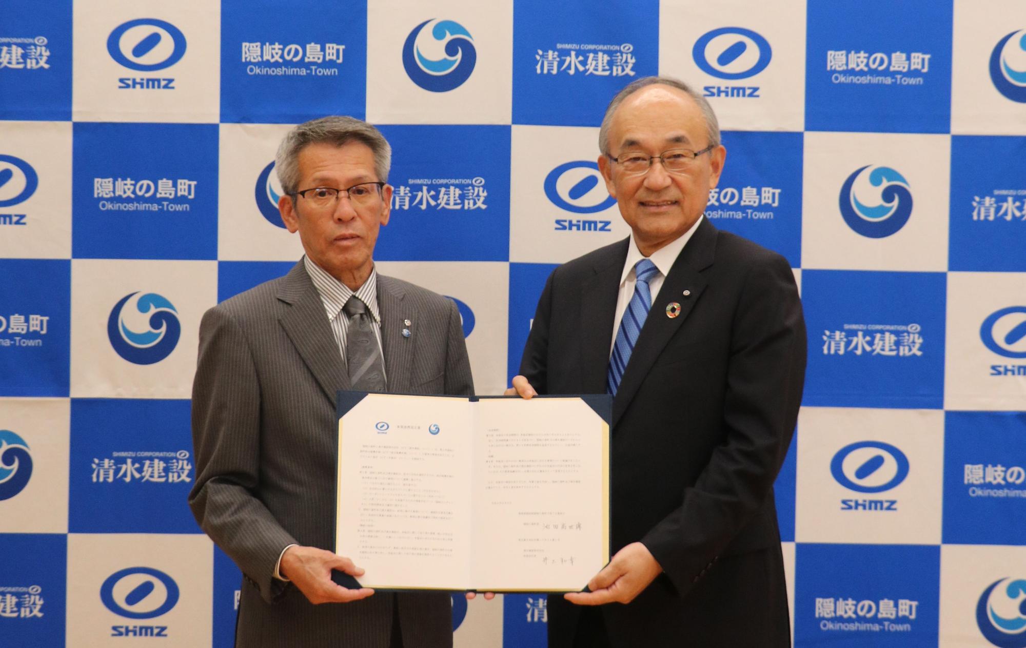 隠岐の島町長と清水建設株式会社の方が事業連携協定の書類を持っている写真