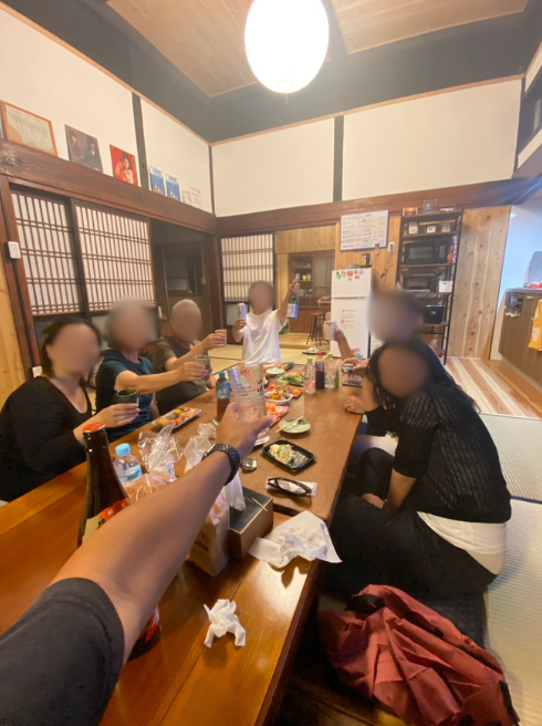 お酒やおつまみが並んだ机を囲んで乾杯をしている様子の写真