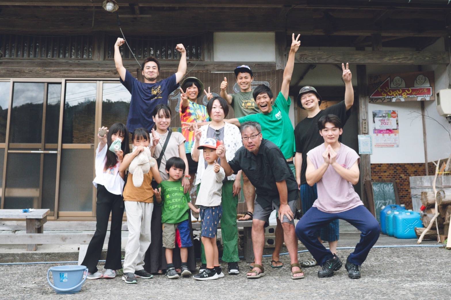 くすぶるハウスを背にした様々なポーズをとる人たちの集合写真