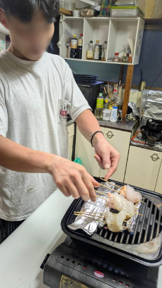 台所で串焼きをしている様子の写真