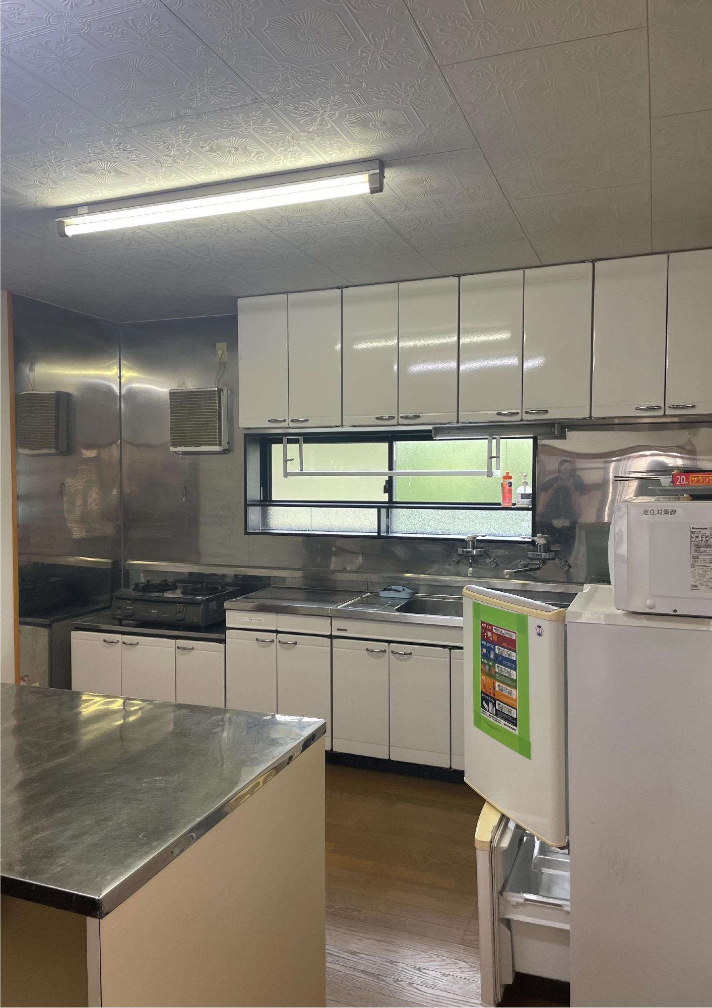 冷蔵庫と電子レンジ、ガスコンロが備え付けられた台所の写真