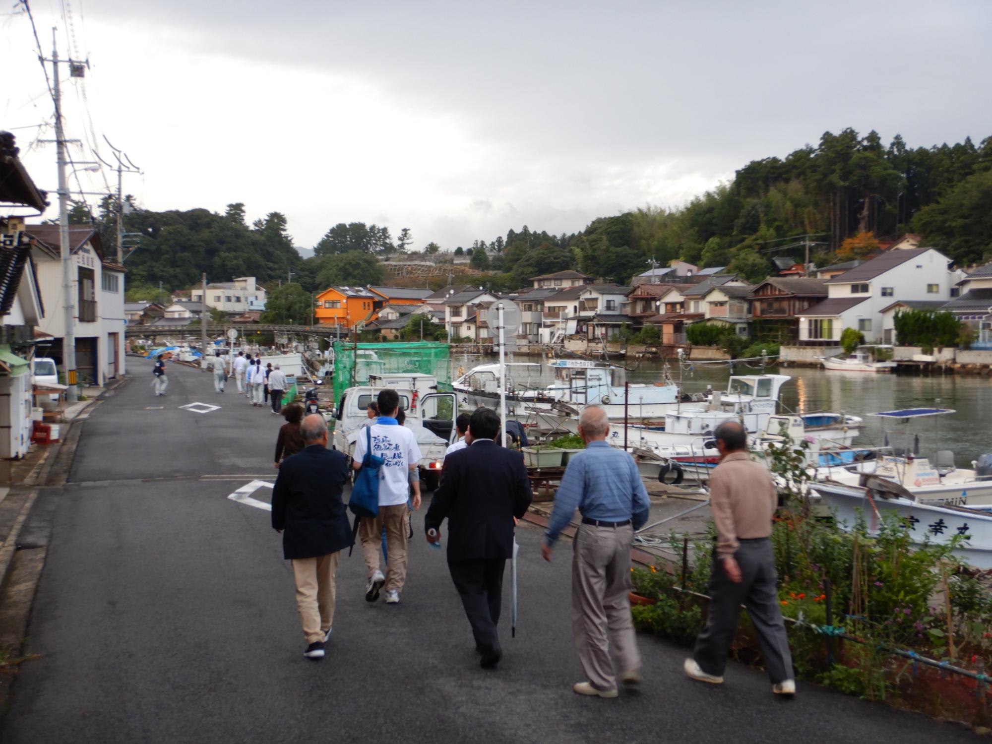 港町を歩く人たちの後ろ姿の写真