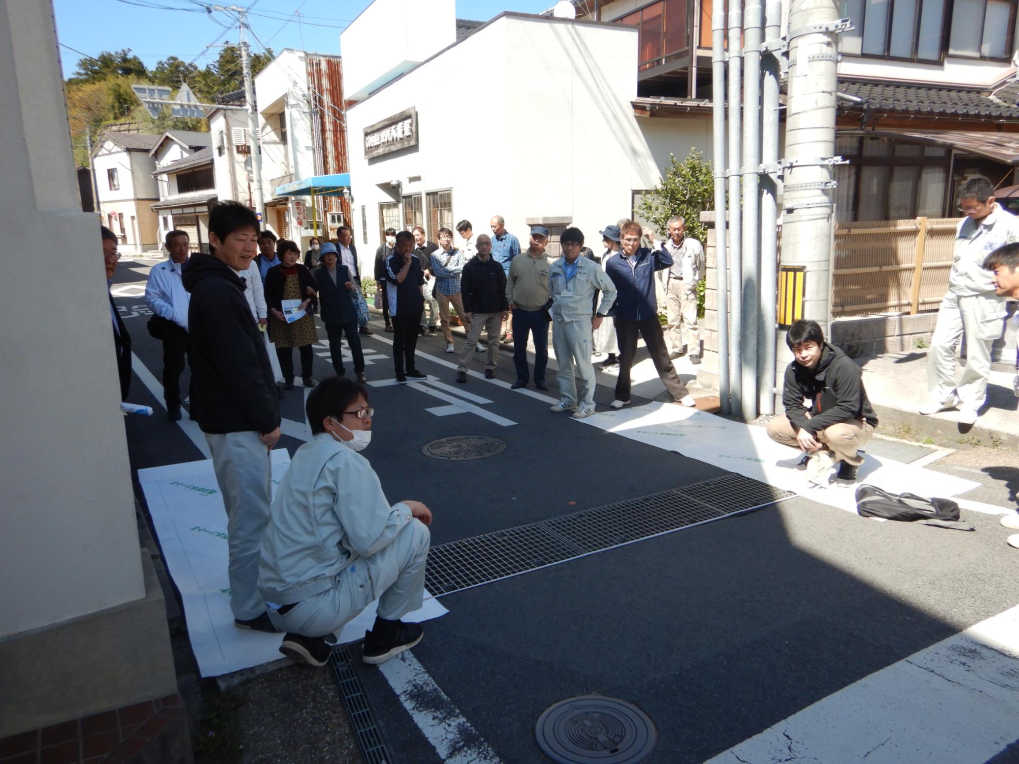 道路に集まり同じ方向を見いている人たちの写真