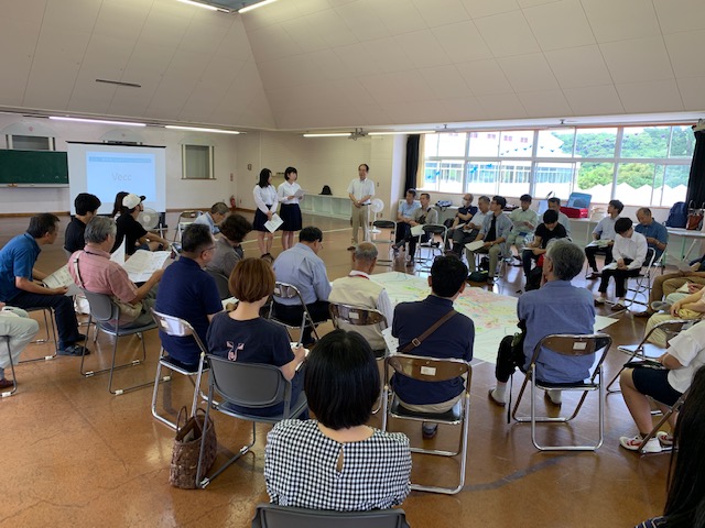 2人の生徒の話を聞いている人たちの後ろ姿の写真