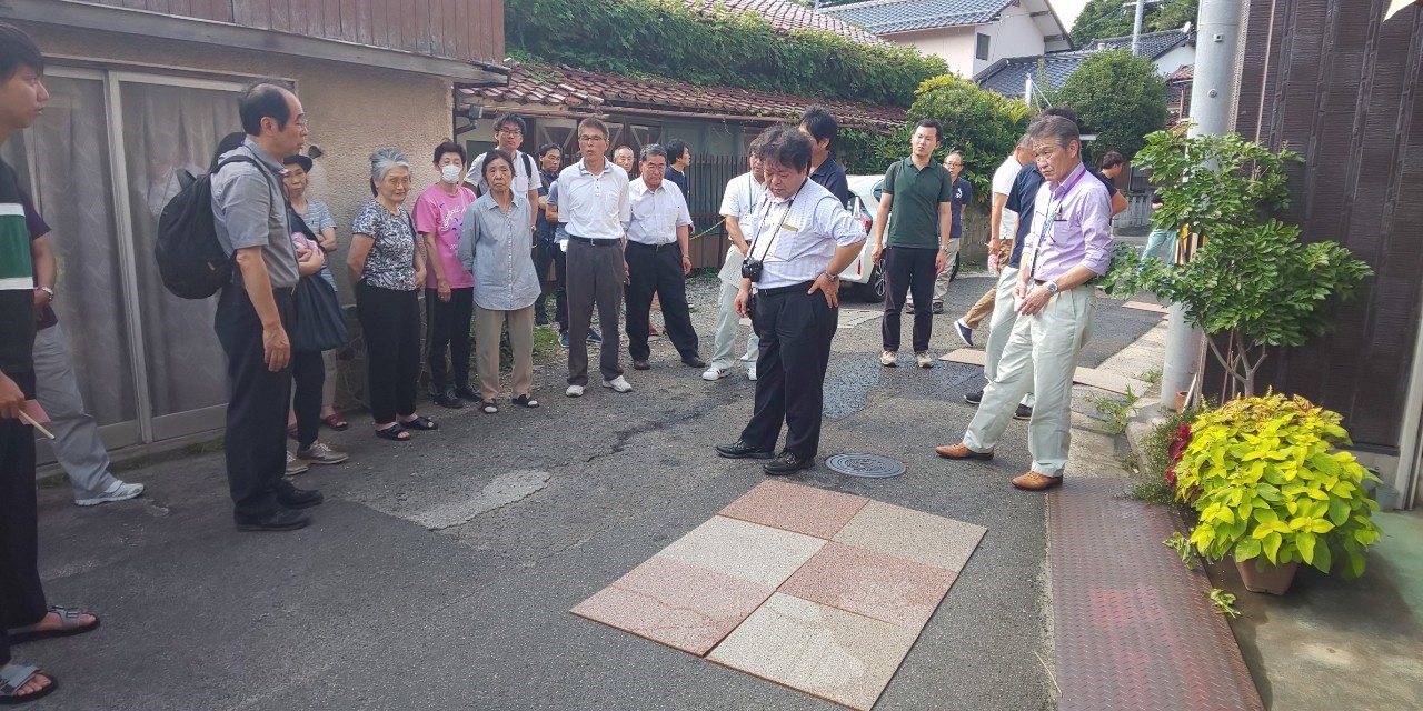 道路に置かれた6つのタイルを見ている人たちの写真