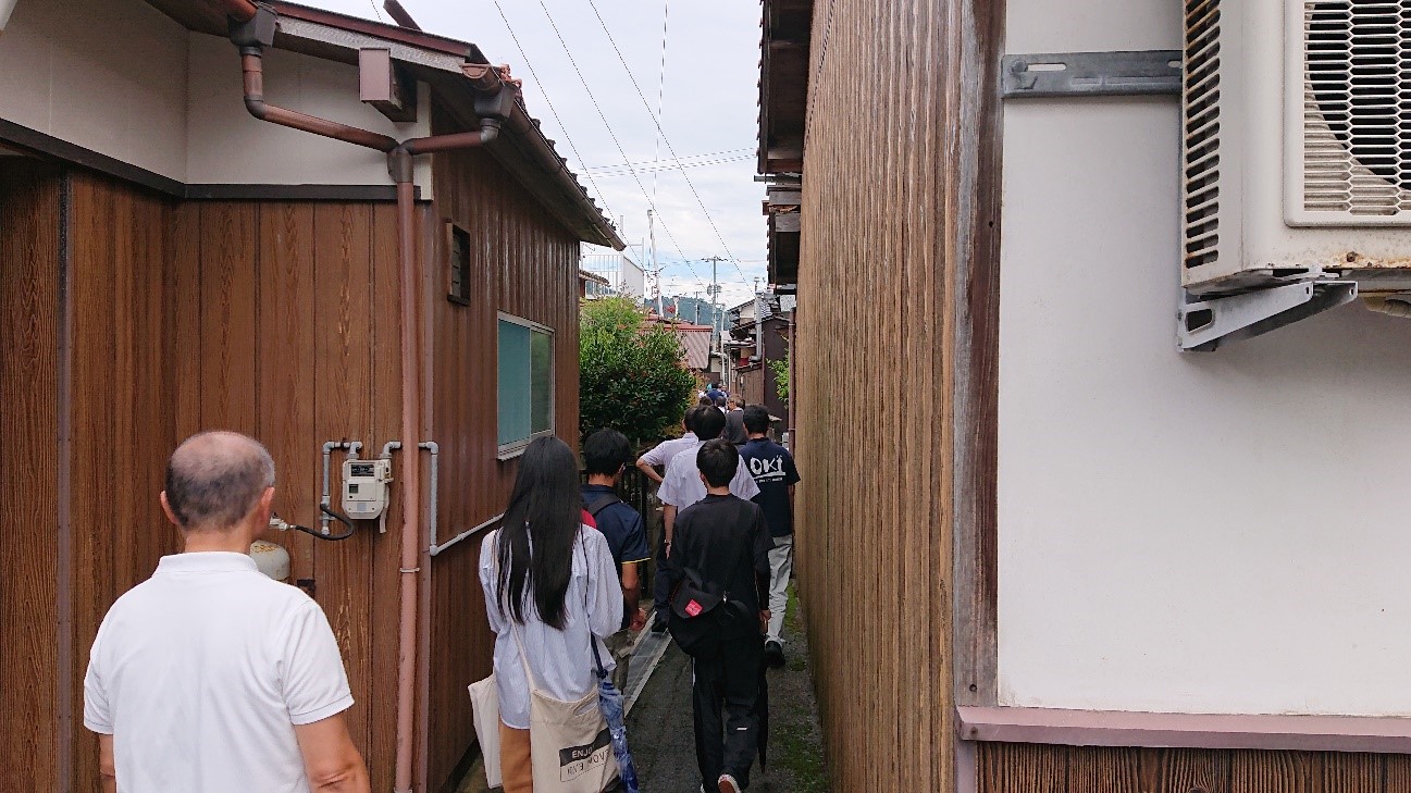 住宅わきの細い道を歩く人たちの写真