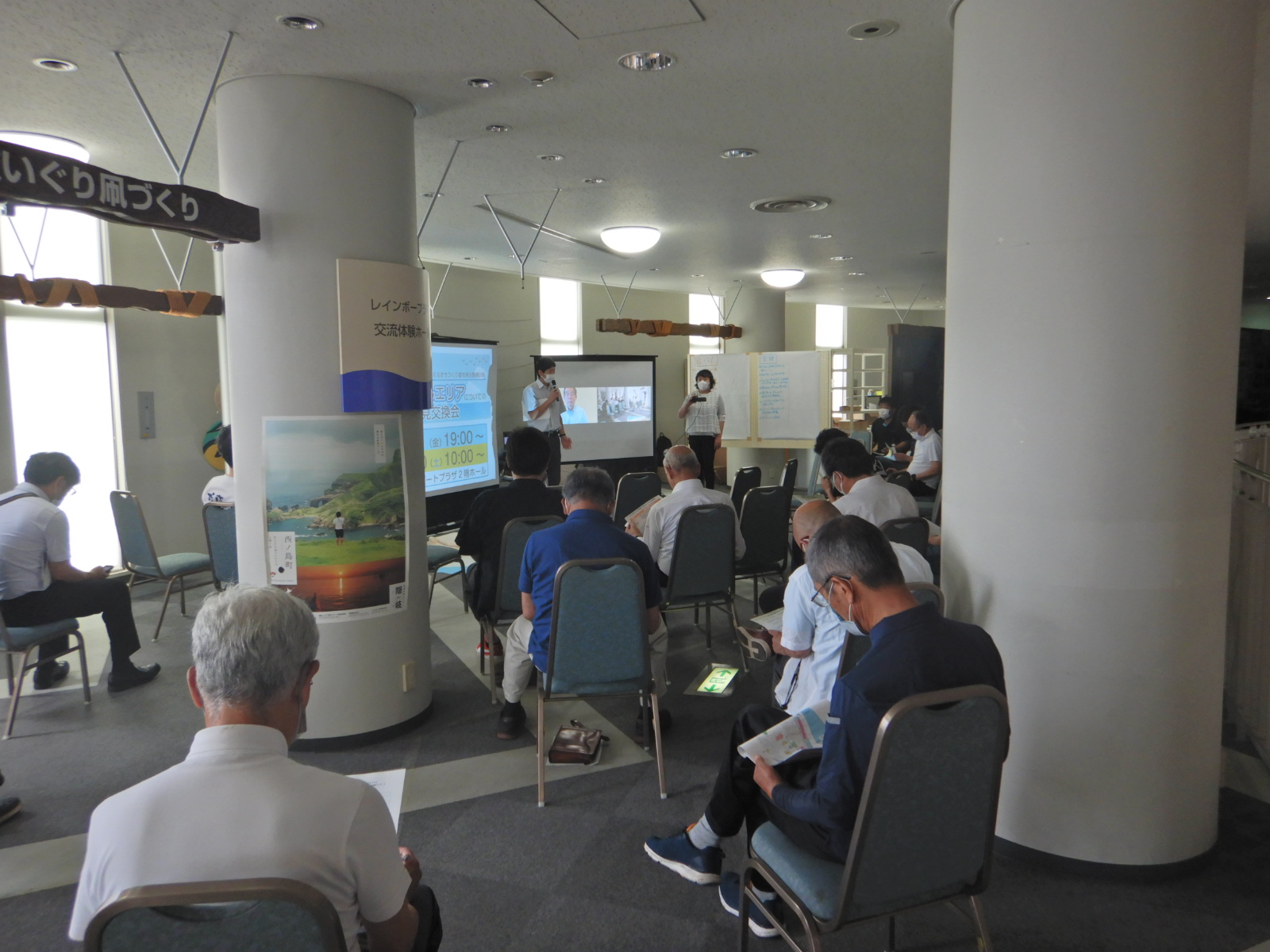 椅子に座って資料を見ている人たちの後ろ姿の写真