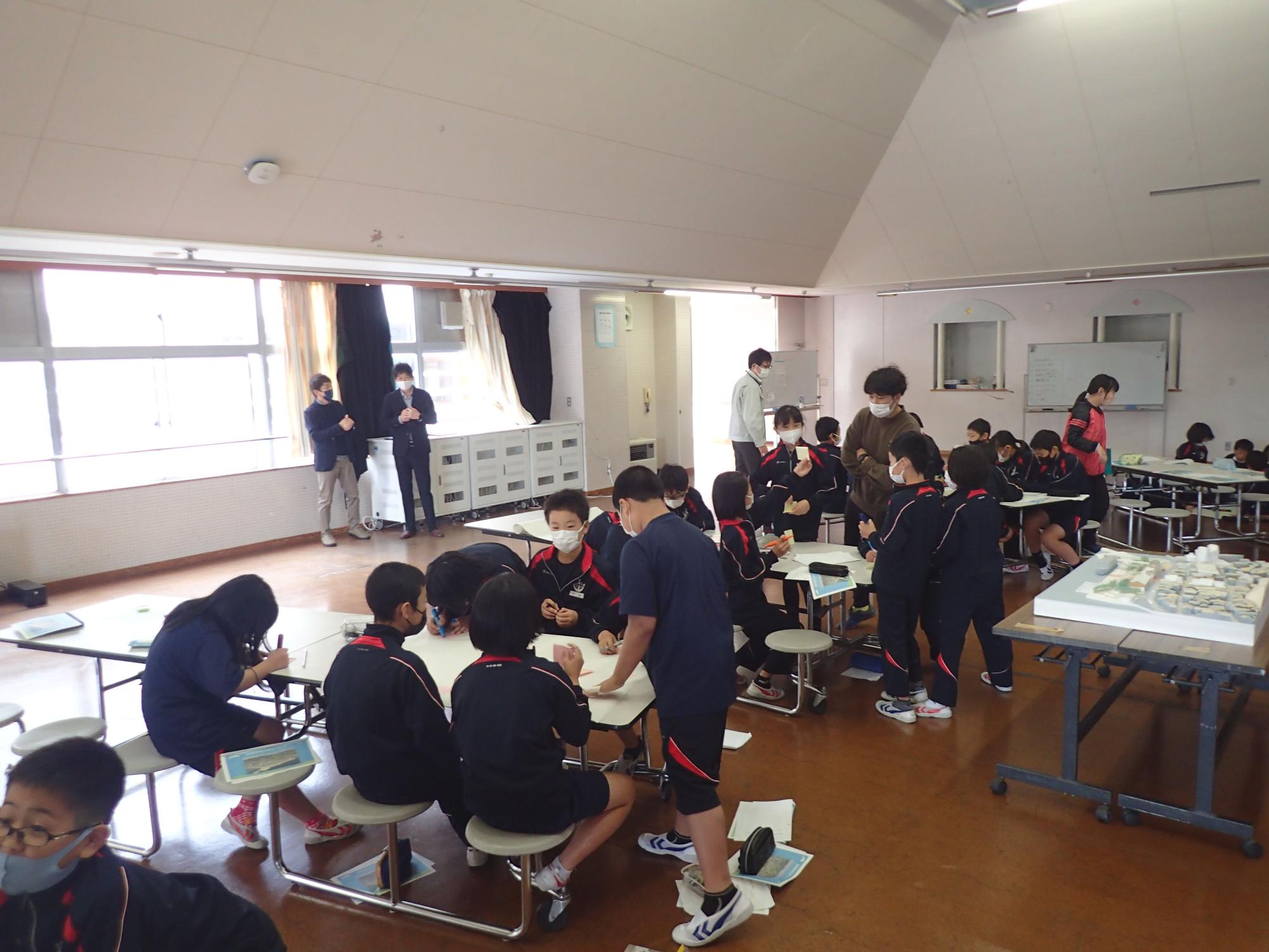 グループワークをしている生徒と見守る先生たちの写真