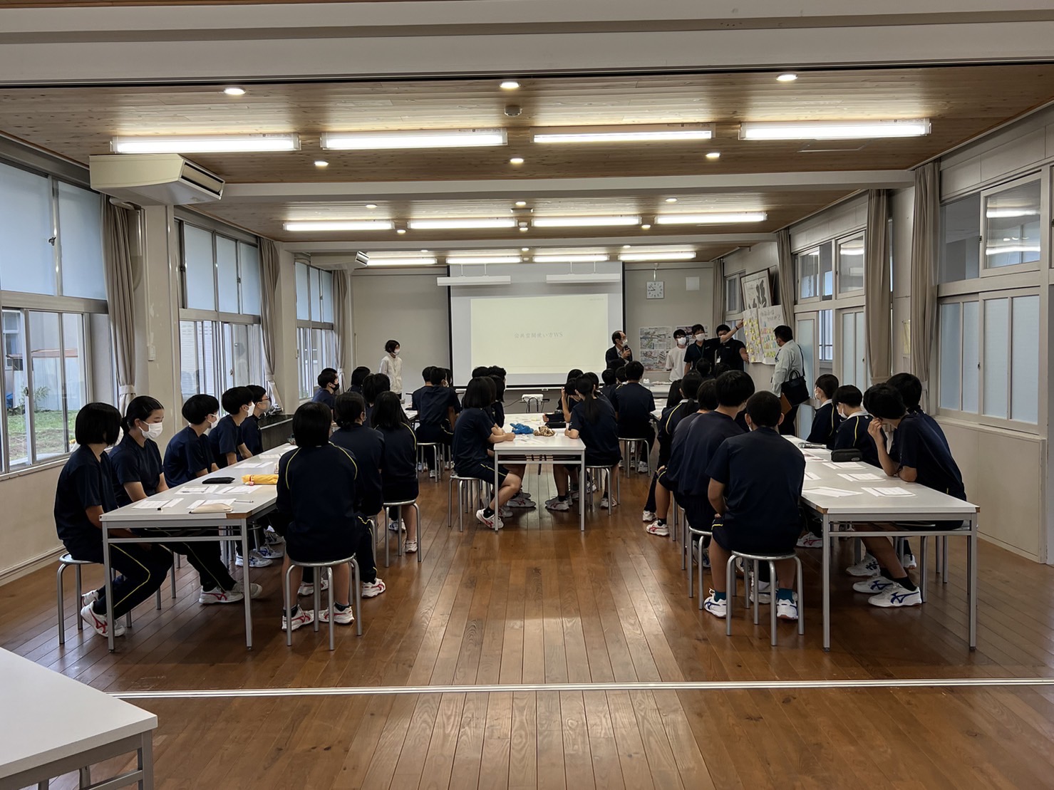 プレゼンをする生徒たちを見ている生徒たちの後ろ姿の写真