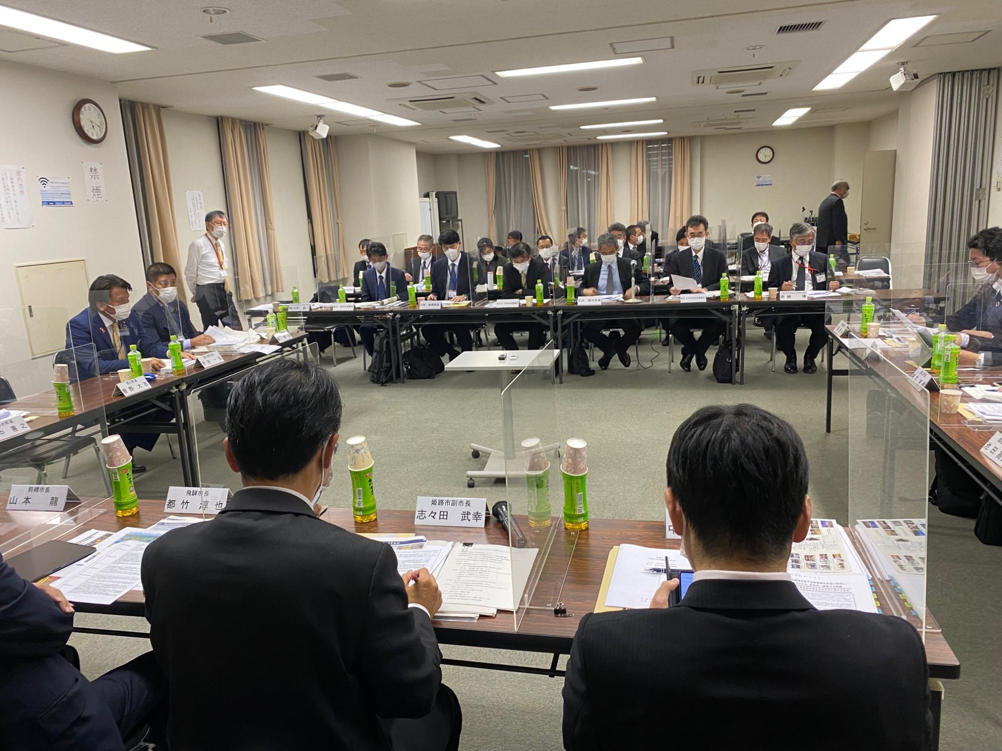 お茶の置かれた席に座って資料を確認するスーツ姿の人たちの写真