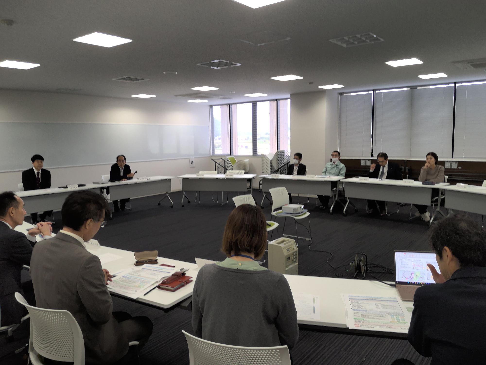 円形に並んだ席で資料やノートパソコンを見ている人たちの写真