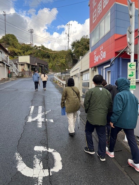 大人たちが複数人でまとまって道路を歩いている写真