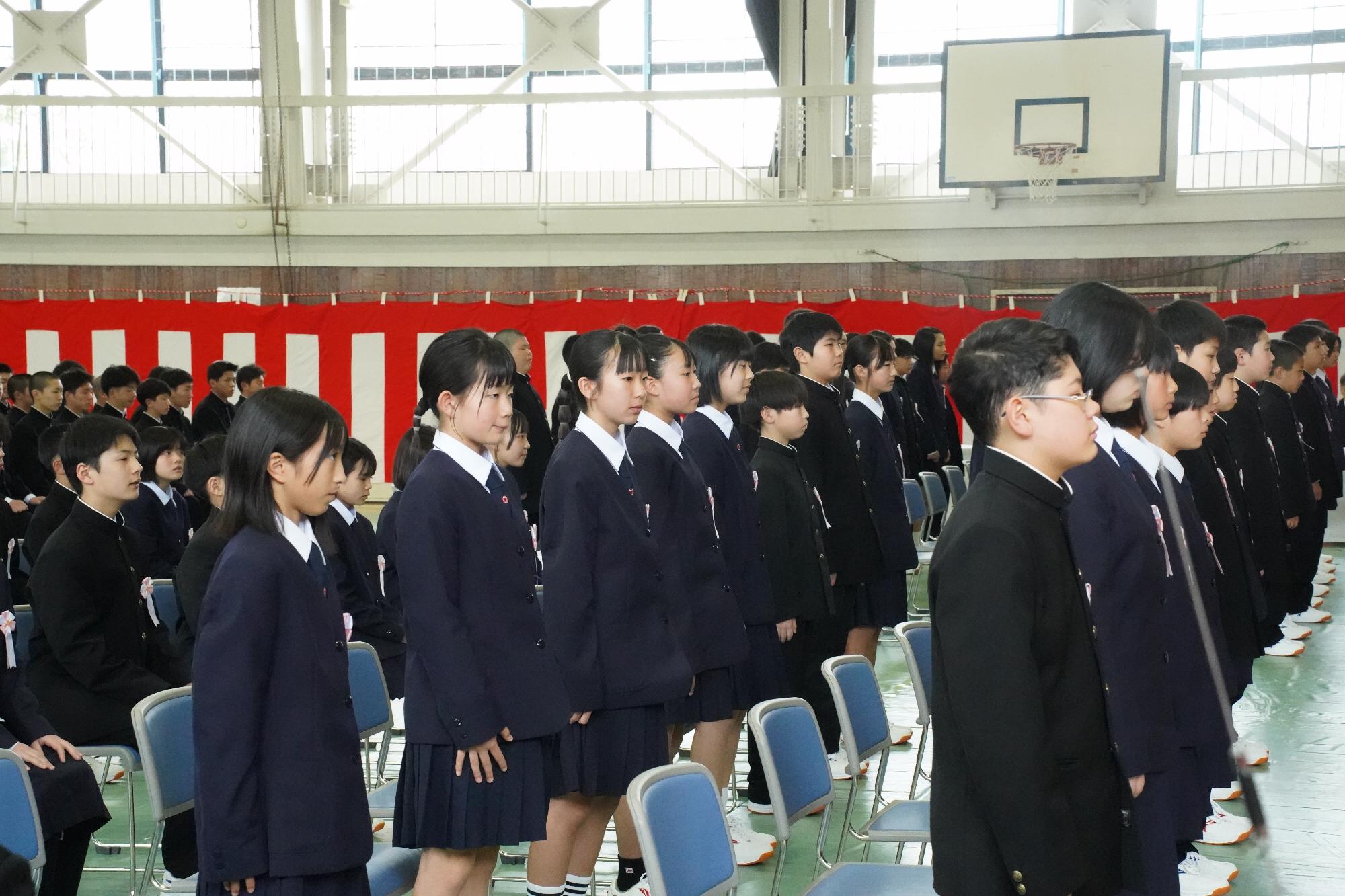 入学式で起立している新一年生たち