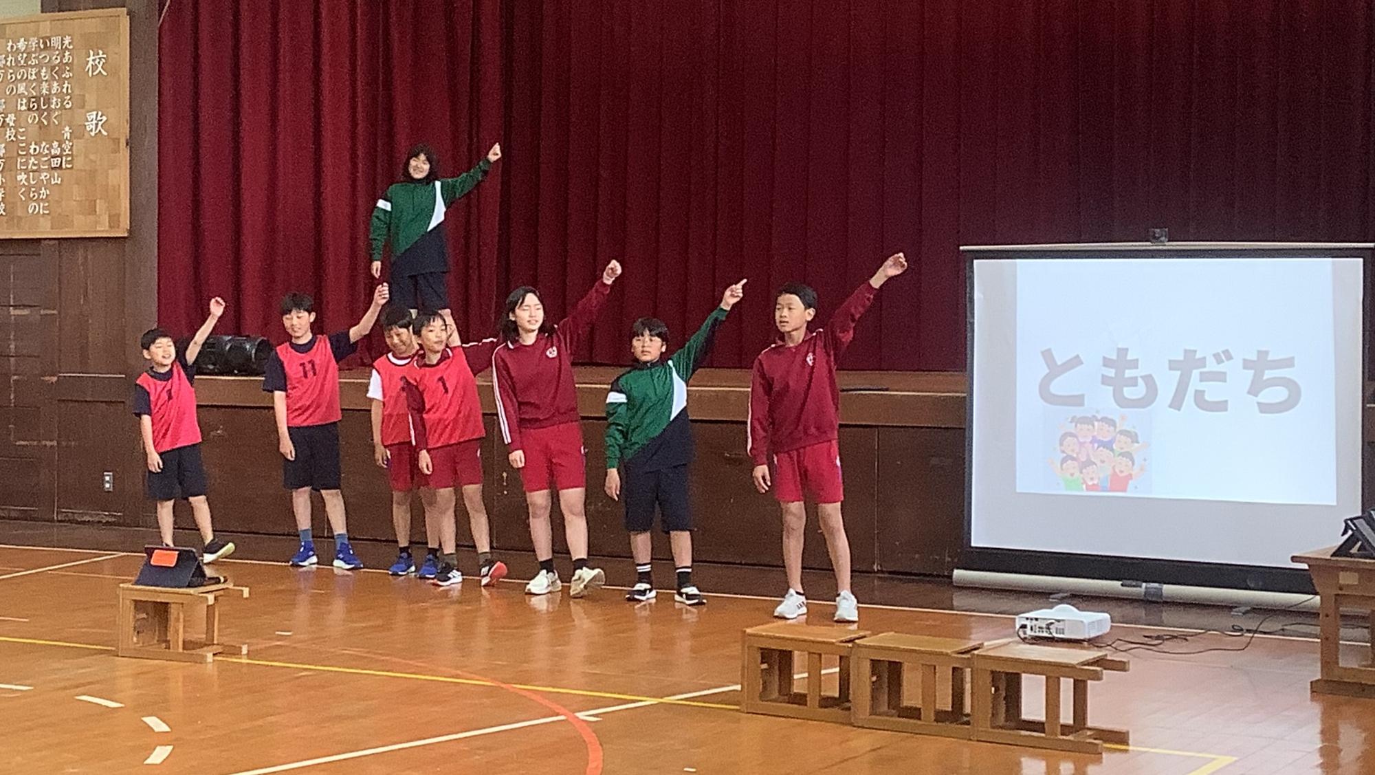 体育館正面に立ち、演劇をする児童たち
