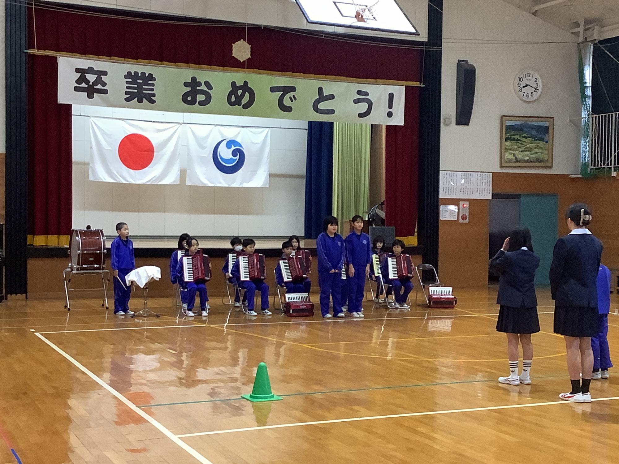 校歌引継ぎ式で6年生から引き継いで楽器を弾く5年生が映った写真