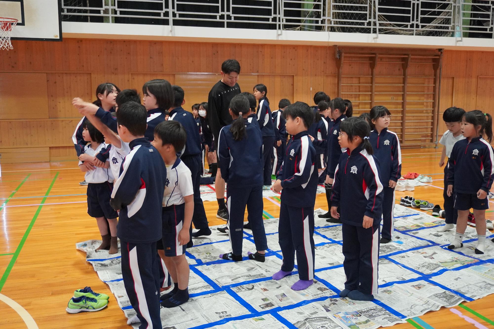 体育館の中で新聞紙を踏んで遊んでいる児童の様子