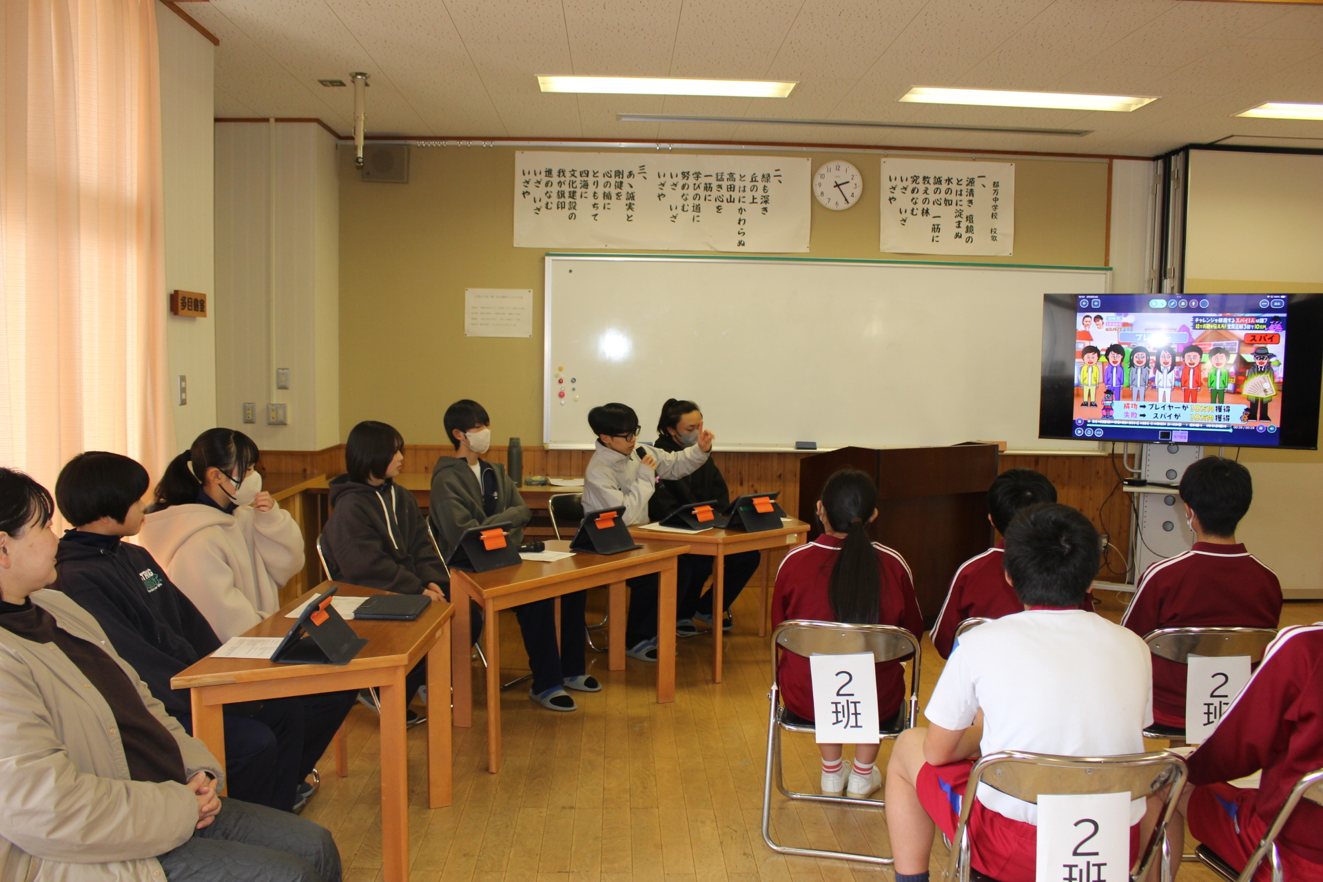 都万中学校の一日入学で中学校2年生が新1年生となる予定の児童を迎えている写真