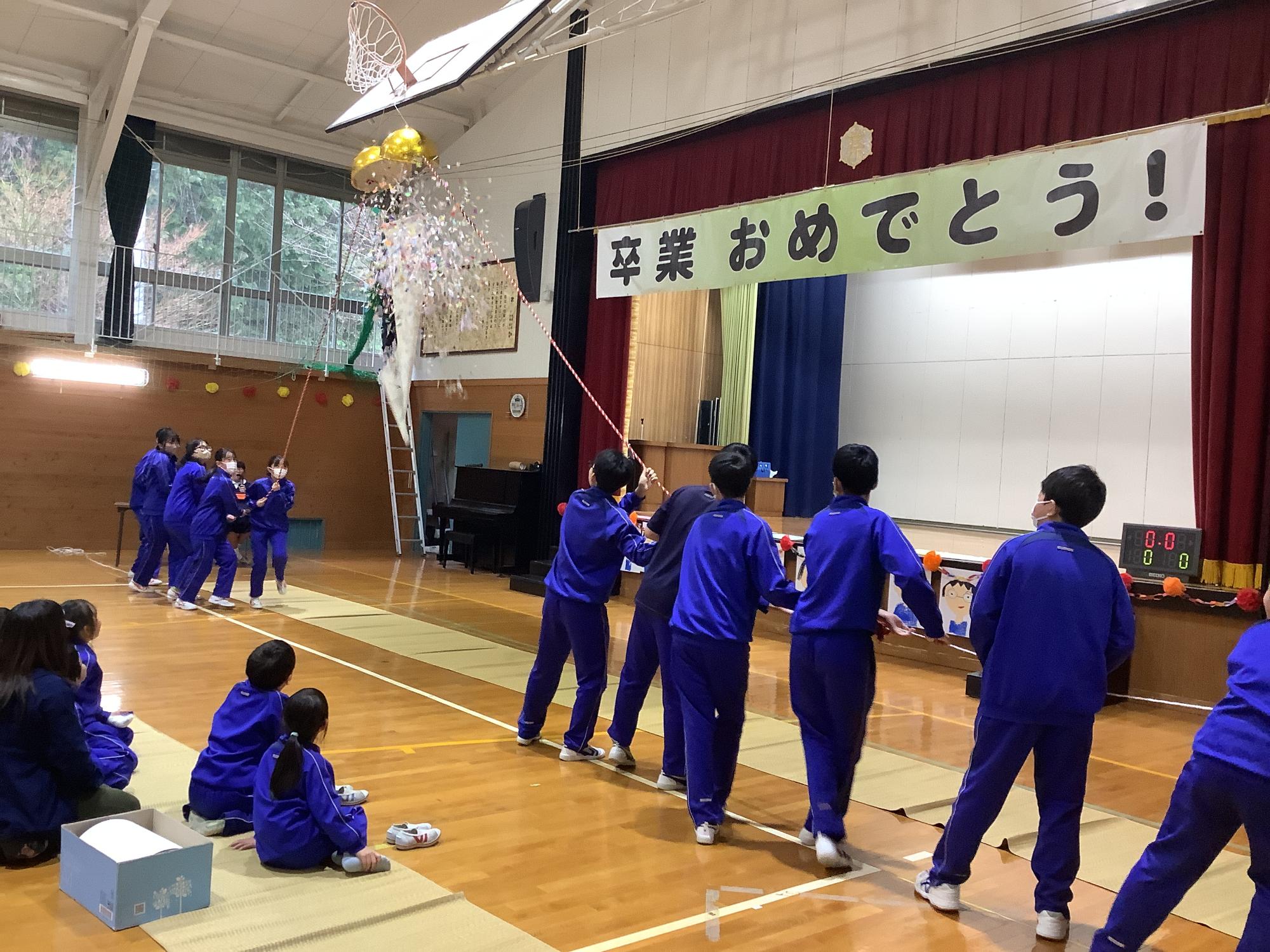 6年生を送る会で設置されたくす玉を割る6年生児童の写真