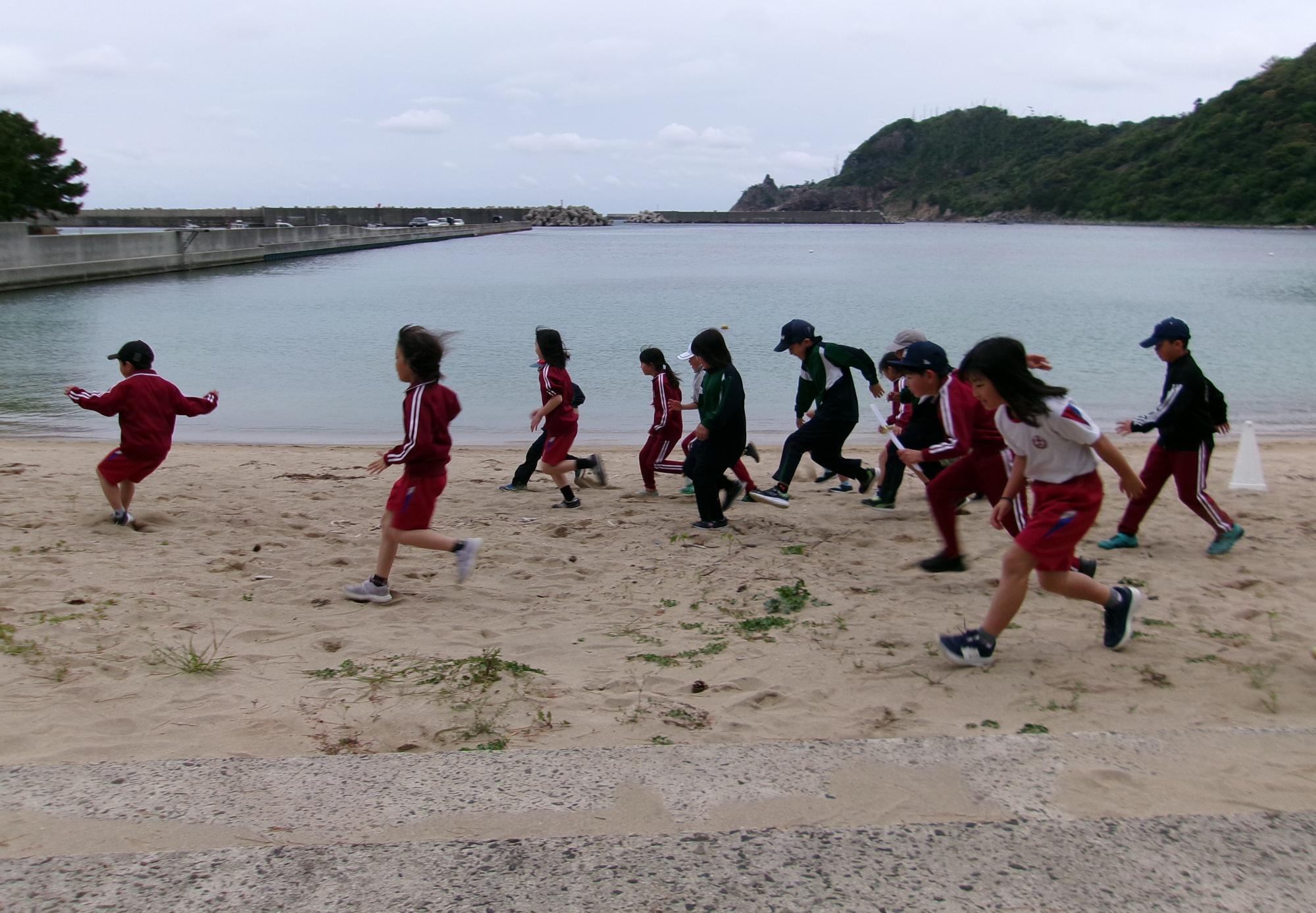 海岸で徒競走をする児童たち
