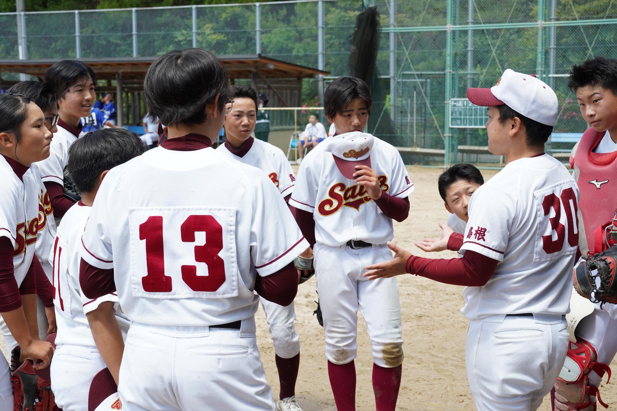 野球でコーチからの話を聞く野球部員の子どもたち