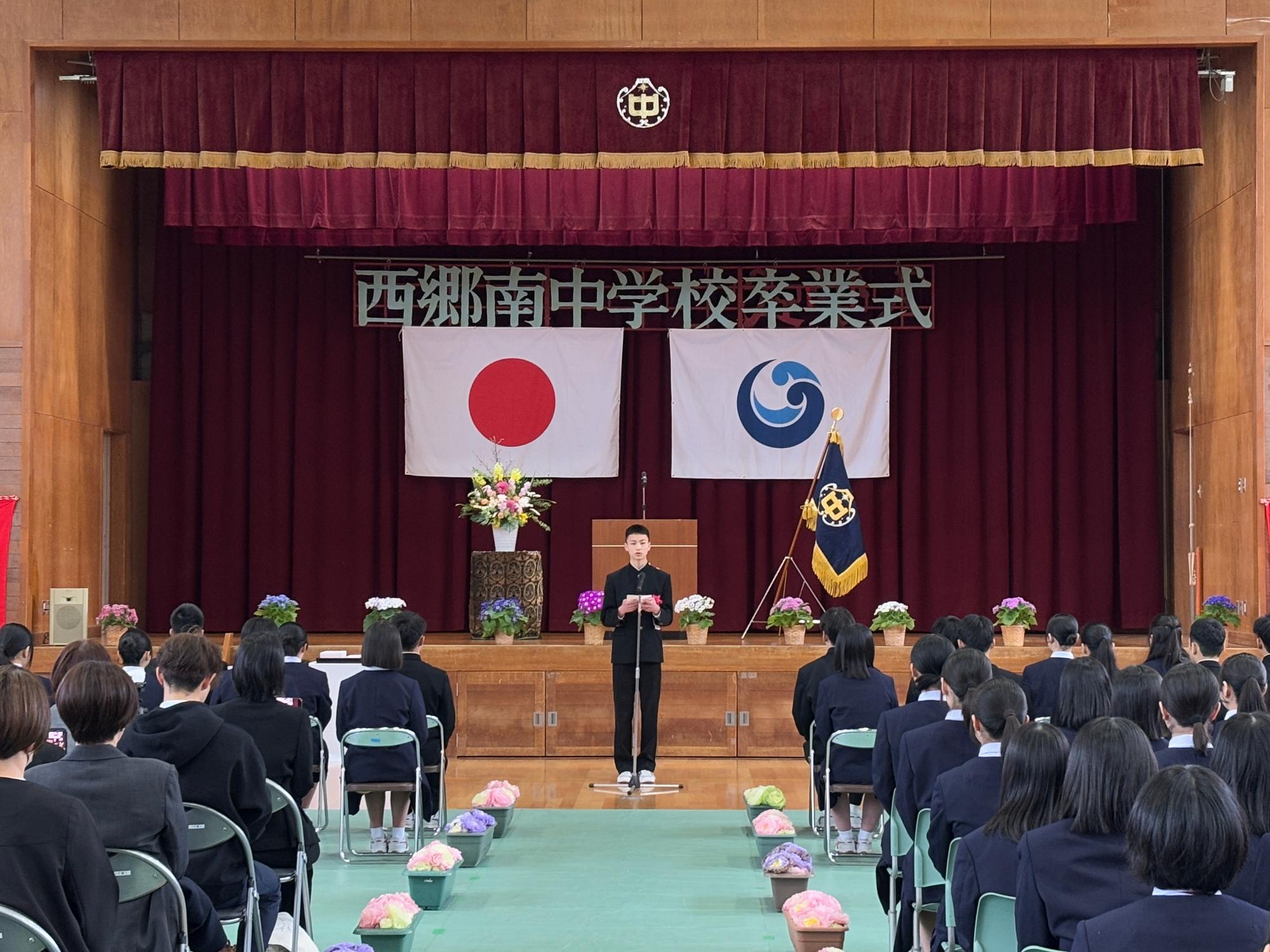 西郷南中学校の卒業式で送辞か答辞を行う生徒が映った写真