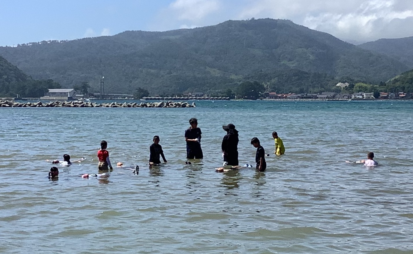高田山を後ろに海水浴を楽しむ児童たち