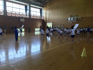 体育館でマスクを付けた児童が先生の指示で整列している様子の写真