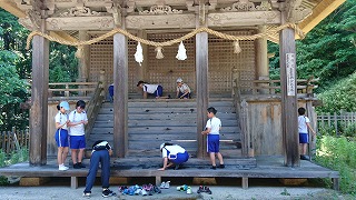 神社の境内を、沢山の児童が手分けして丁寧に掃除をしている様子の写真