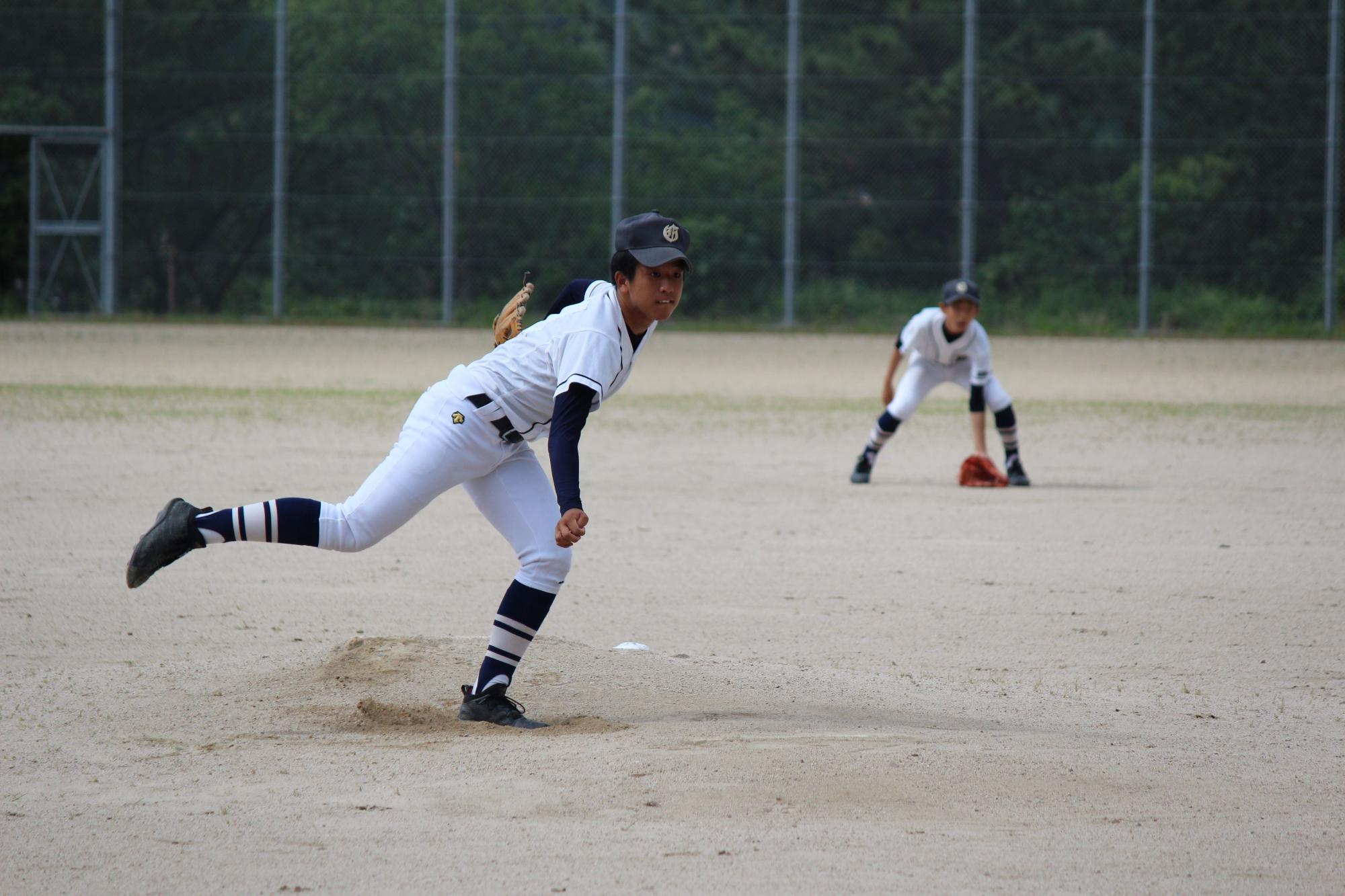 グラウンドで野球の試合中に投球する中学生の写真