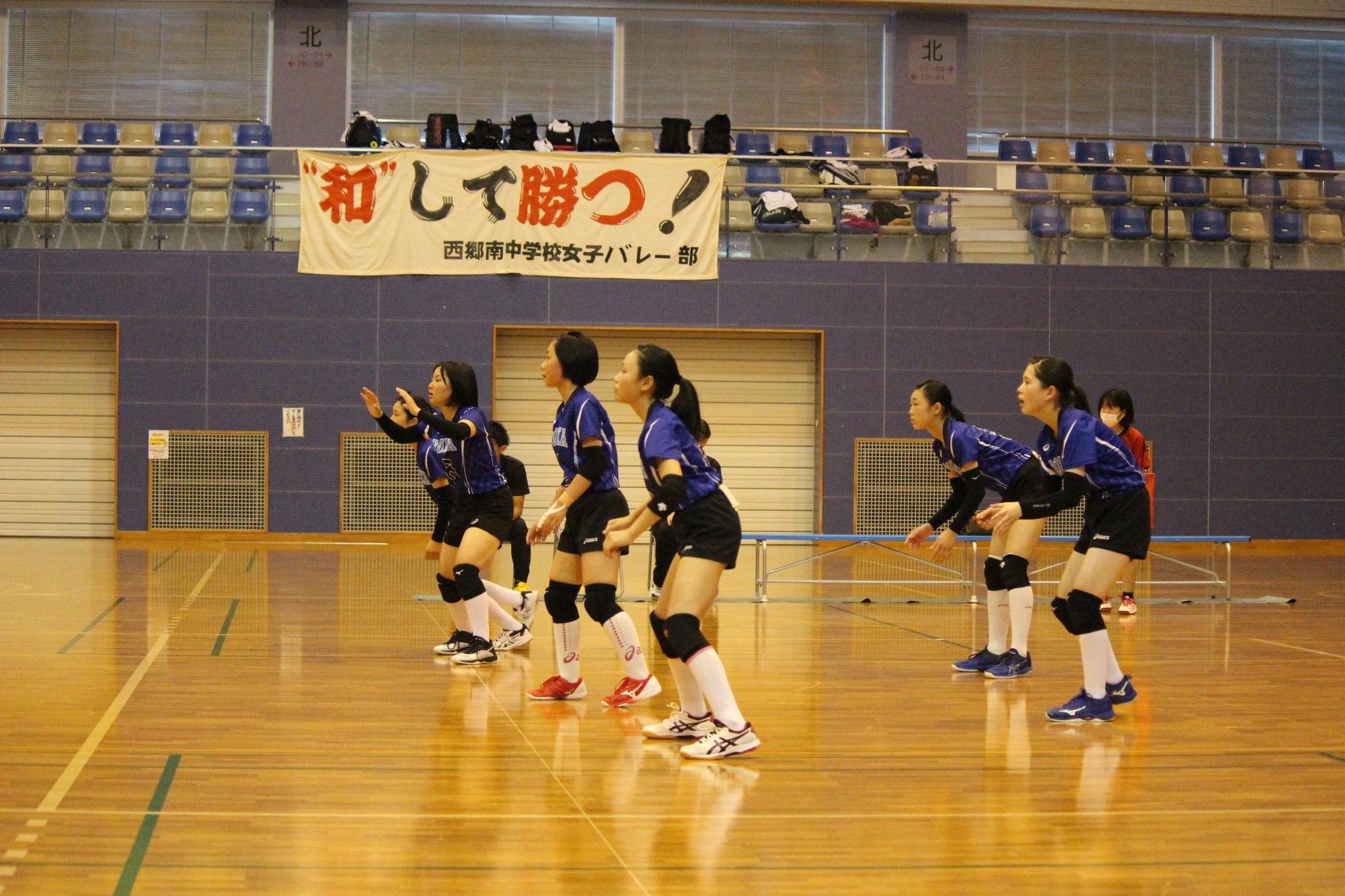 体育館で整列して試合に臨む女子バレーボール部員たちの写真