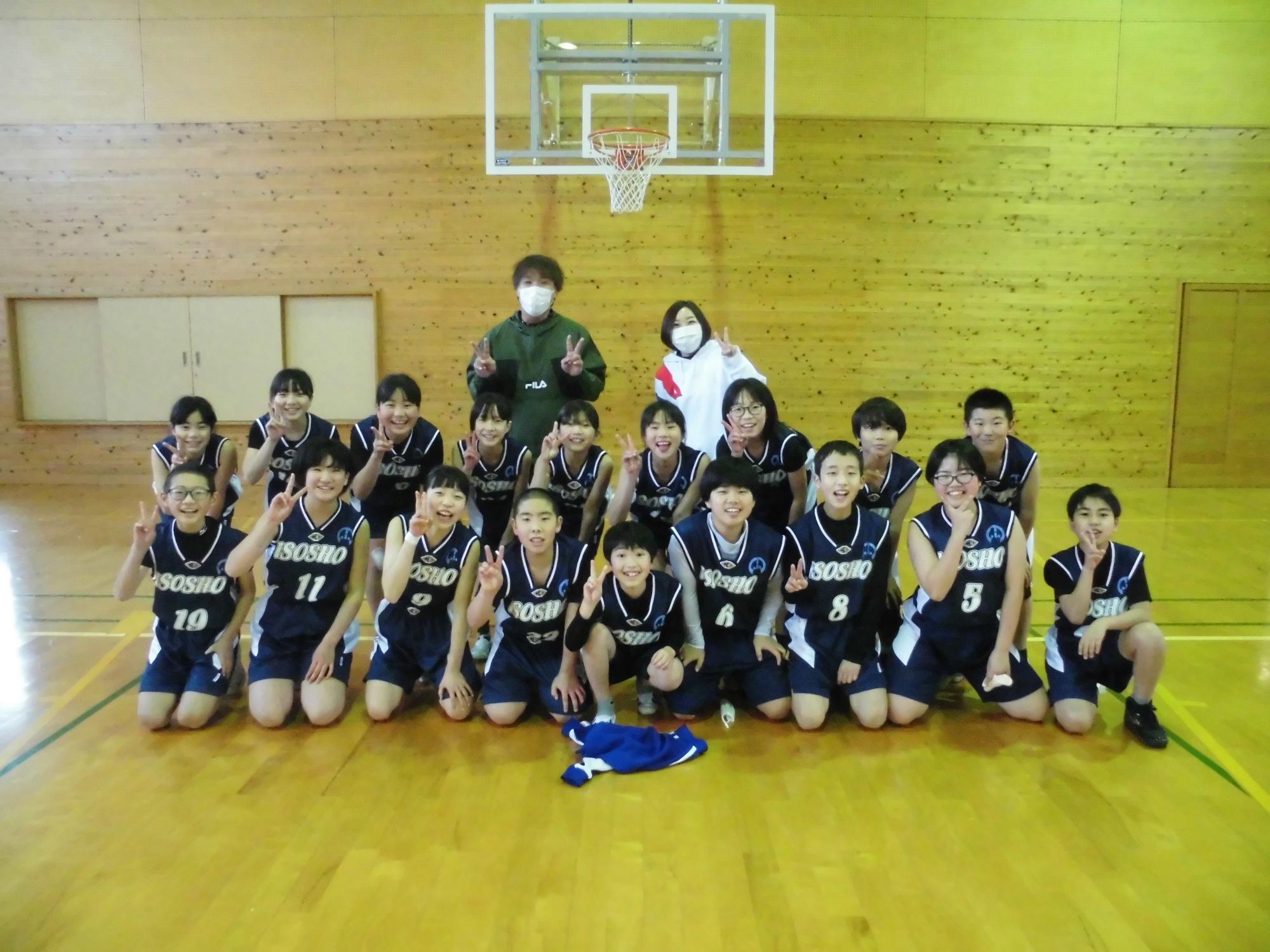 体育館でバスケットボールチームが笑顔で集合写真を撮っている写真