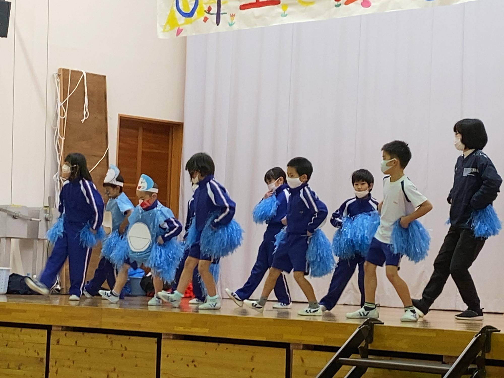 体育館のステージ上で児童たちが踊っている様子の写真