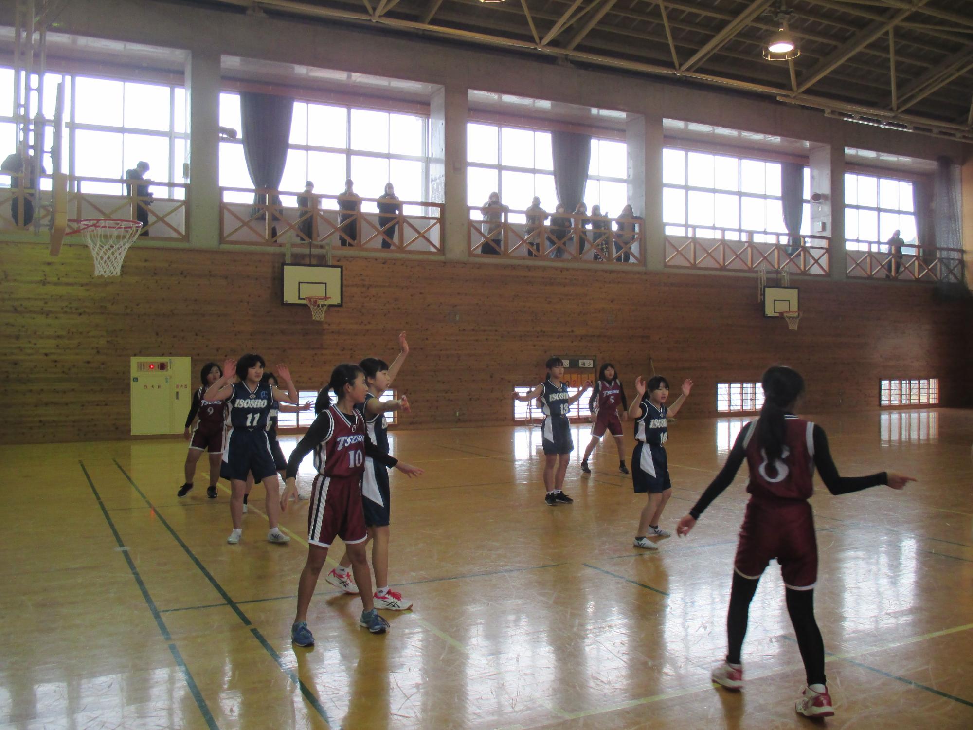 体育館で女子児童たちがバスケットボールの試合をしている写真