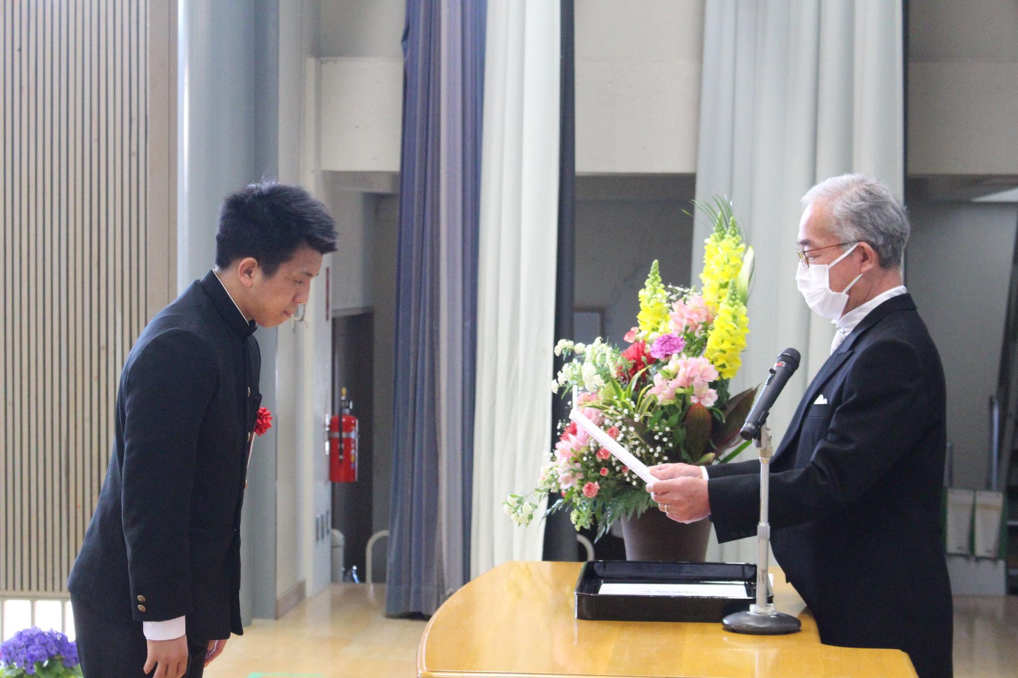 卒業式で校長先生から卒業証書を受け取る生徒の写真