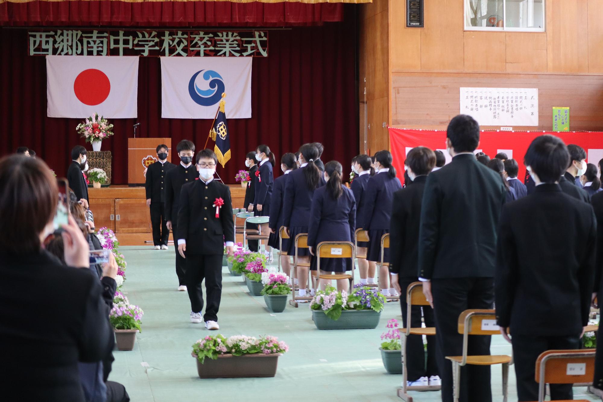 卒業式で卒業生が少し緊張した面持ちで退場している写真