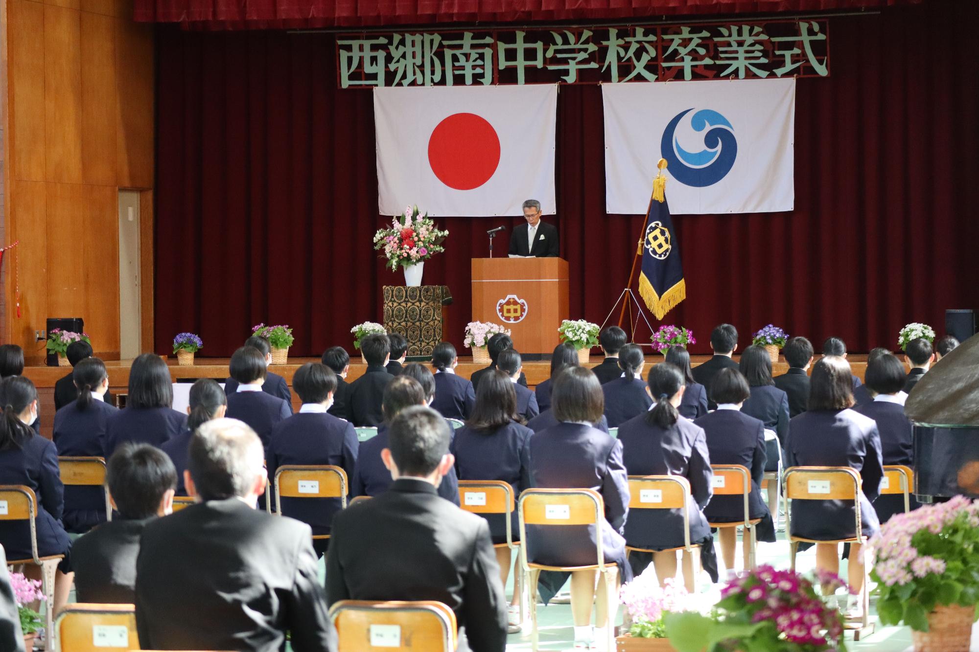 体育館で校長先生が卒業生に向けて卒業式の式辞を述べている写真