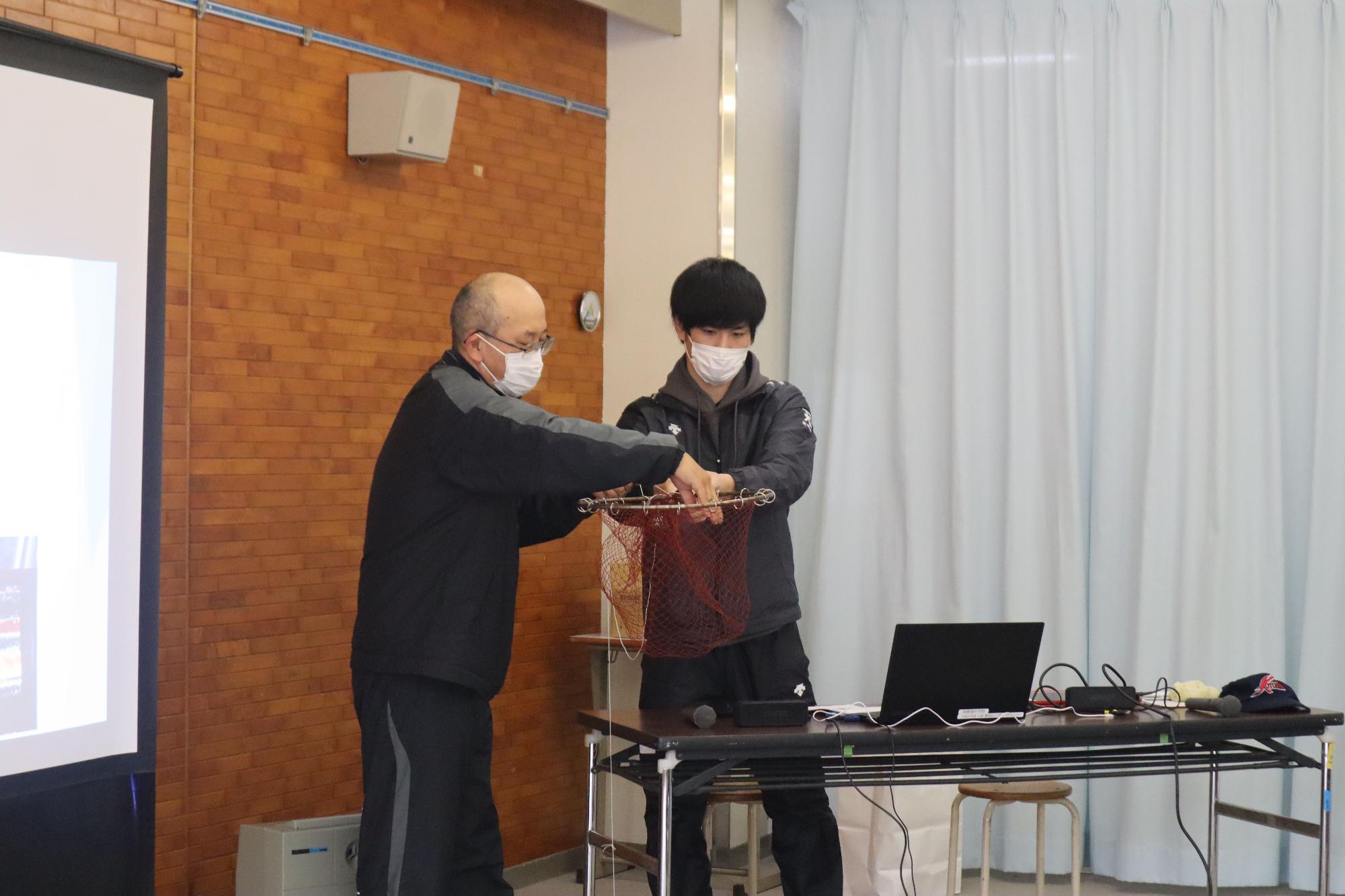 教室で講師と生徒が網を使って説明している写真