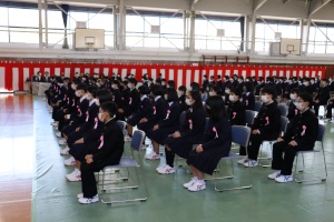 体育館の舞台前で制服を着た生徒たちが整然と座って入学式に臨んでいる写真