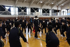 体育館でジャージを着た生徒たちが準備運動をしている写真