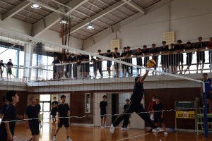 体育館で男子生徒がネット際でボールをブロックしている写真