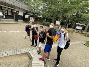 公園の入口でリュックを背負った生徒たちが並んでポーズを取っている写真