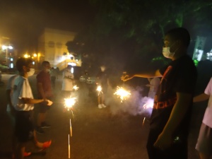 夜の屋外で生徒たちが手持ち花火を楽しんでいる写真